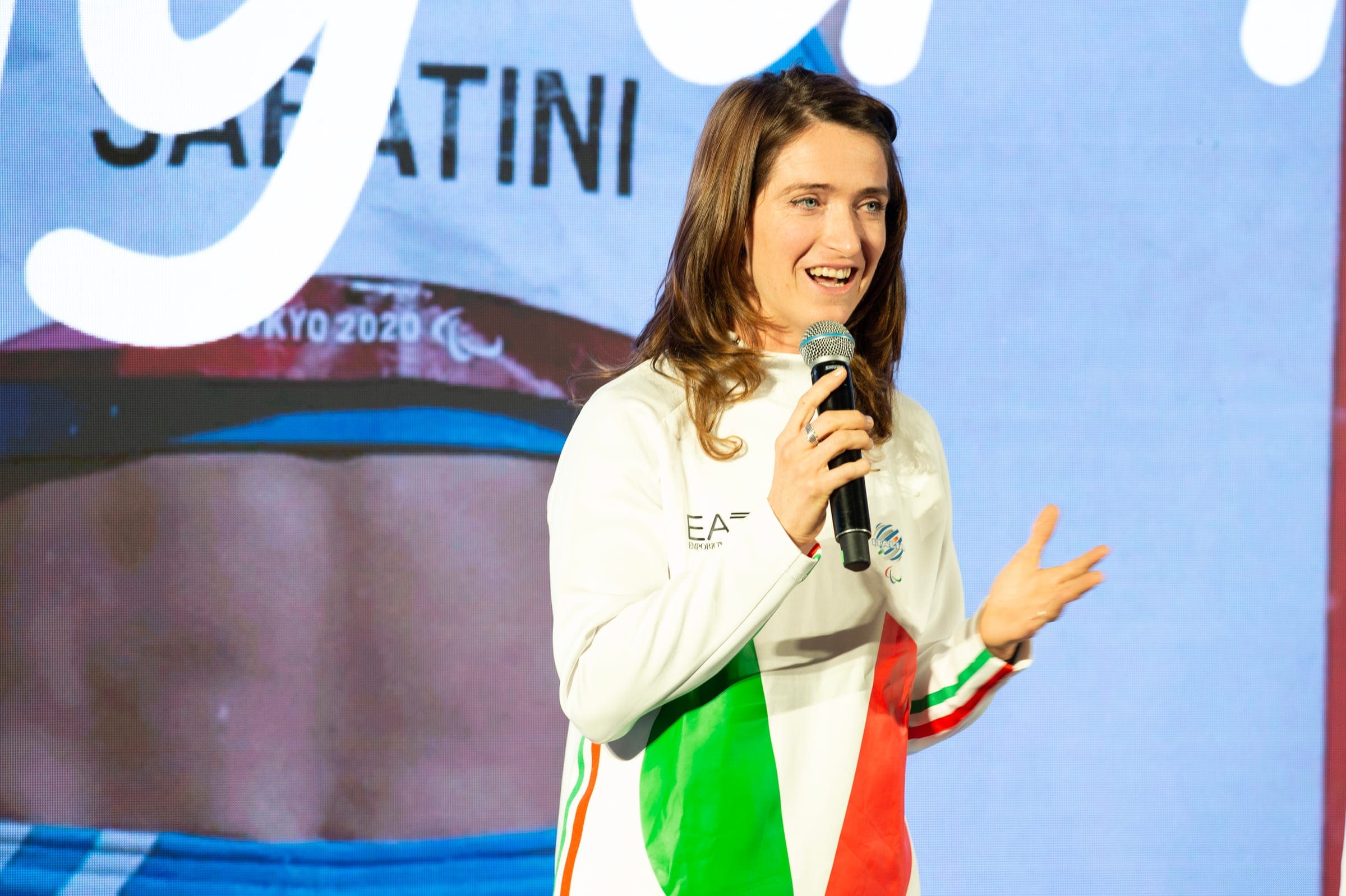 Martina Caironi parla al microfono con la tuta bianca della nazionale italiana a Meet Milano Cortina 2026, nel 2023